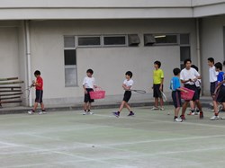 軟式テニスで、男子児童がボールを打ち終わった瞬間