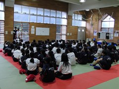 体育館で実行委員長の話を聞く生徒たち