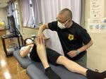 後半実技の様子。講師が「足三里（あしさんり）」というツボの位置を説明している写真。※足三里穴は膝の少し下にあります。