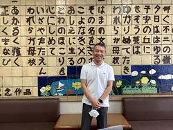 お招きした高橋医師。笑顔で応じてくださいました。陶板に彫ってある横浜市立盲特別支援学校校歌の前にて。