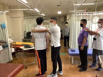 →画像1   患者さんの体幹の回旋運動の説明をする近藤先生。施術者の腕 が患者さんの背中に沿うように回旋運動を行うと、視力にハンディ があっても患者さんの動きが分かります。