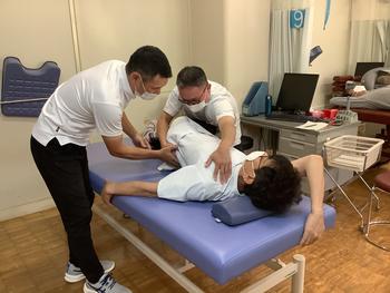 →画像2   ダイナミックな脊椎のストレッチング。参加生徒に指導してい る様子。