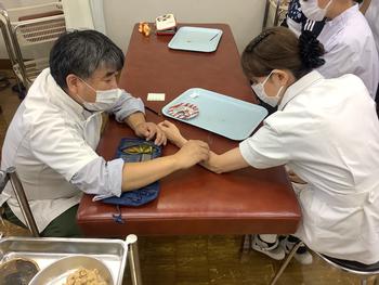 福島先生が受講者の前腕部に深谷灸法による施灸を行っている写真
